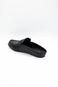 A single black leather loafer slip-on shoe with a decorative strap detail across the vamp, shown from a side profile view on a clean white background.