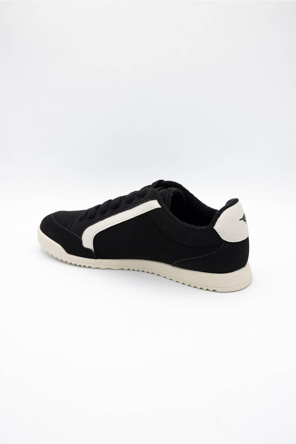 A black low-top sneaker with a contrasting white side stripe, white heel tab, and a white midsole, shown from a side-rear angle on a light gray background.