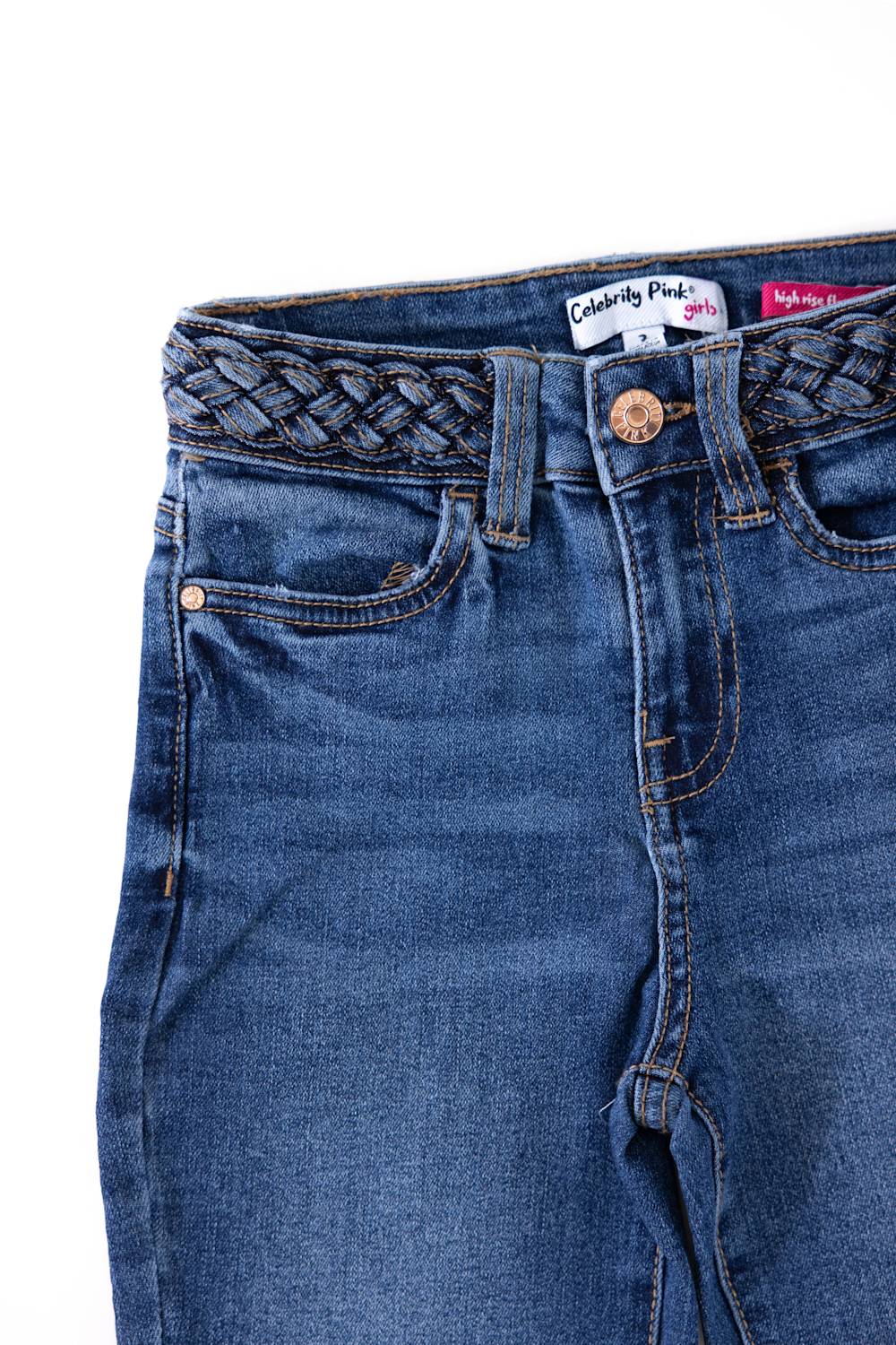 Close-up view of the front waistband and pockets on Celebrity Pink Girls Braided Waistband Flare Jeans in Nancy medium wash