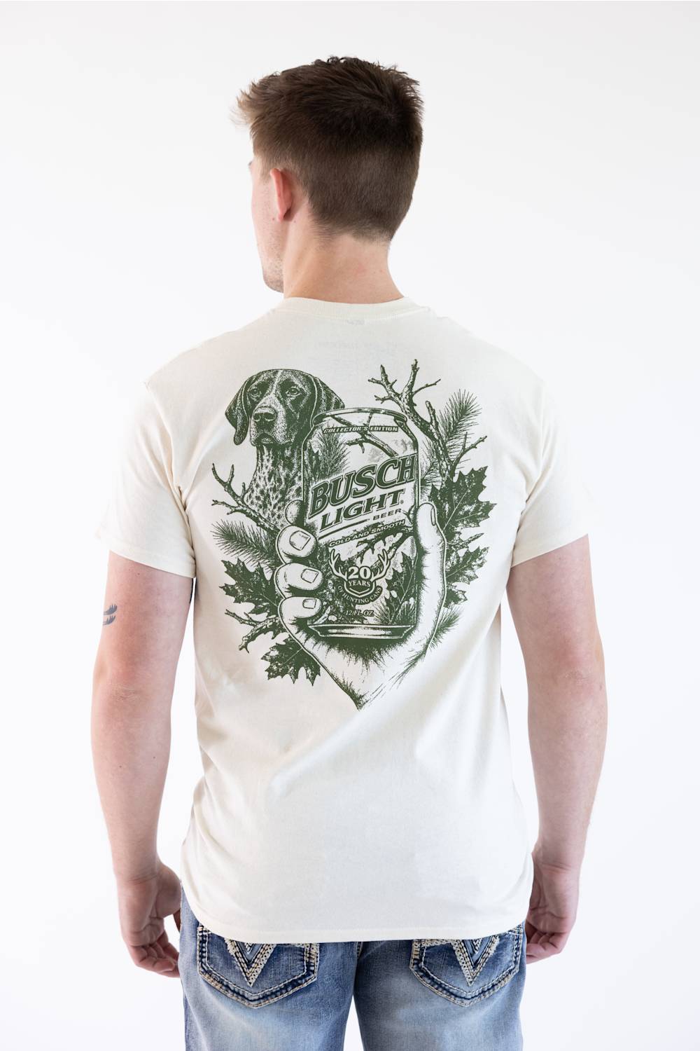 A man viewed from behind wearing a white t-shirt with a large green graphic print on the back featuring a dog, antlers, and the text 'Irish Light'.
