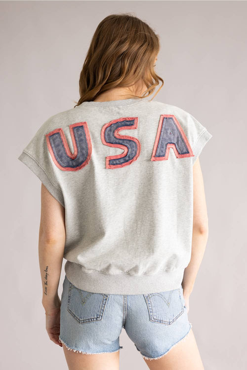 Person wearing a gray sleeveless shirt with 'USA' printed on the back, standing against a plain background.