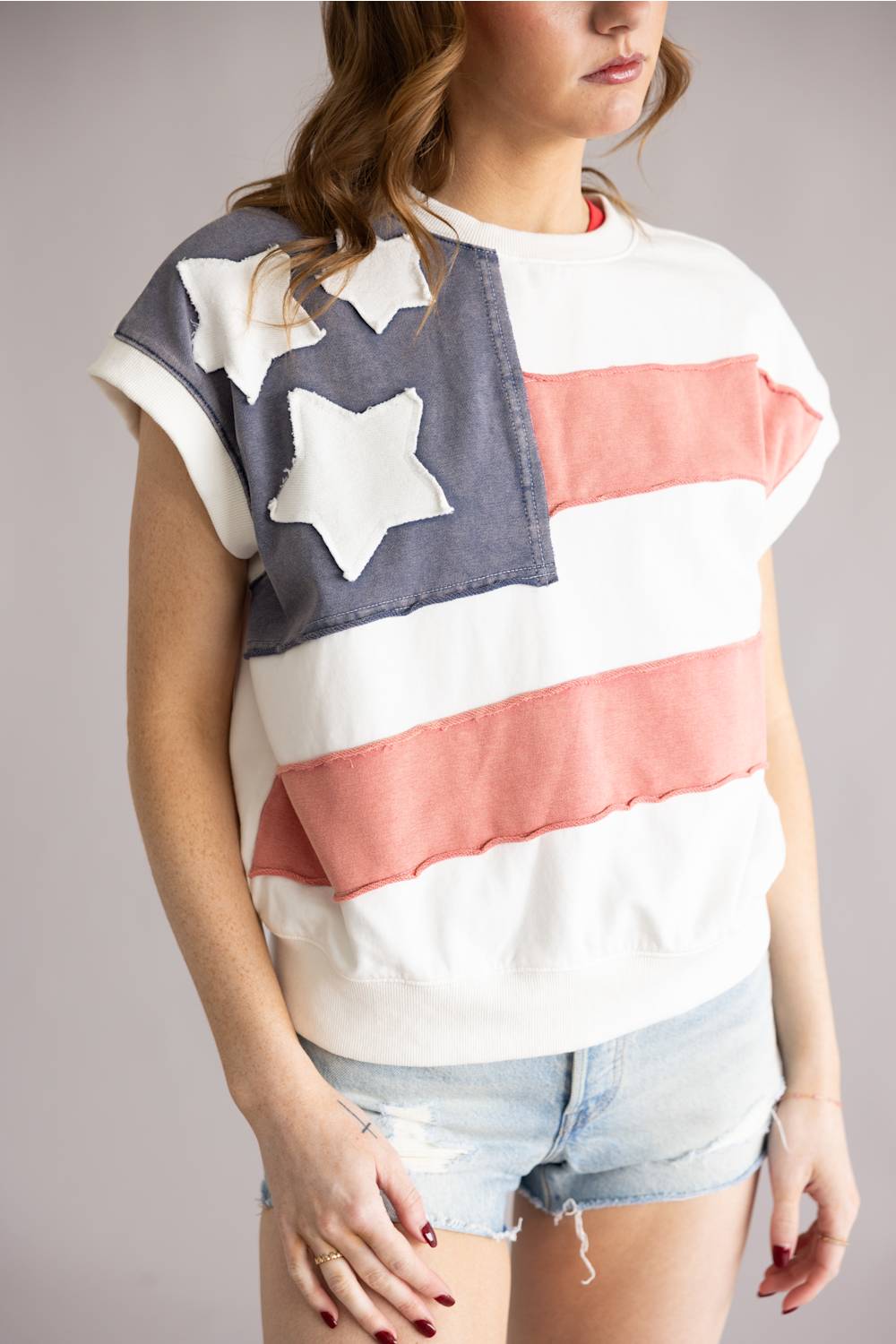 Person wearing a sleeveless top with American flag design on a plain background