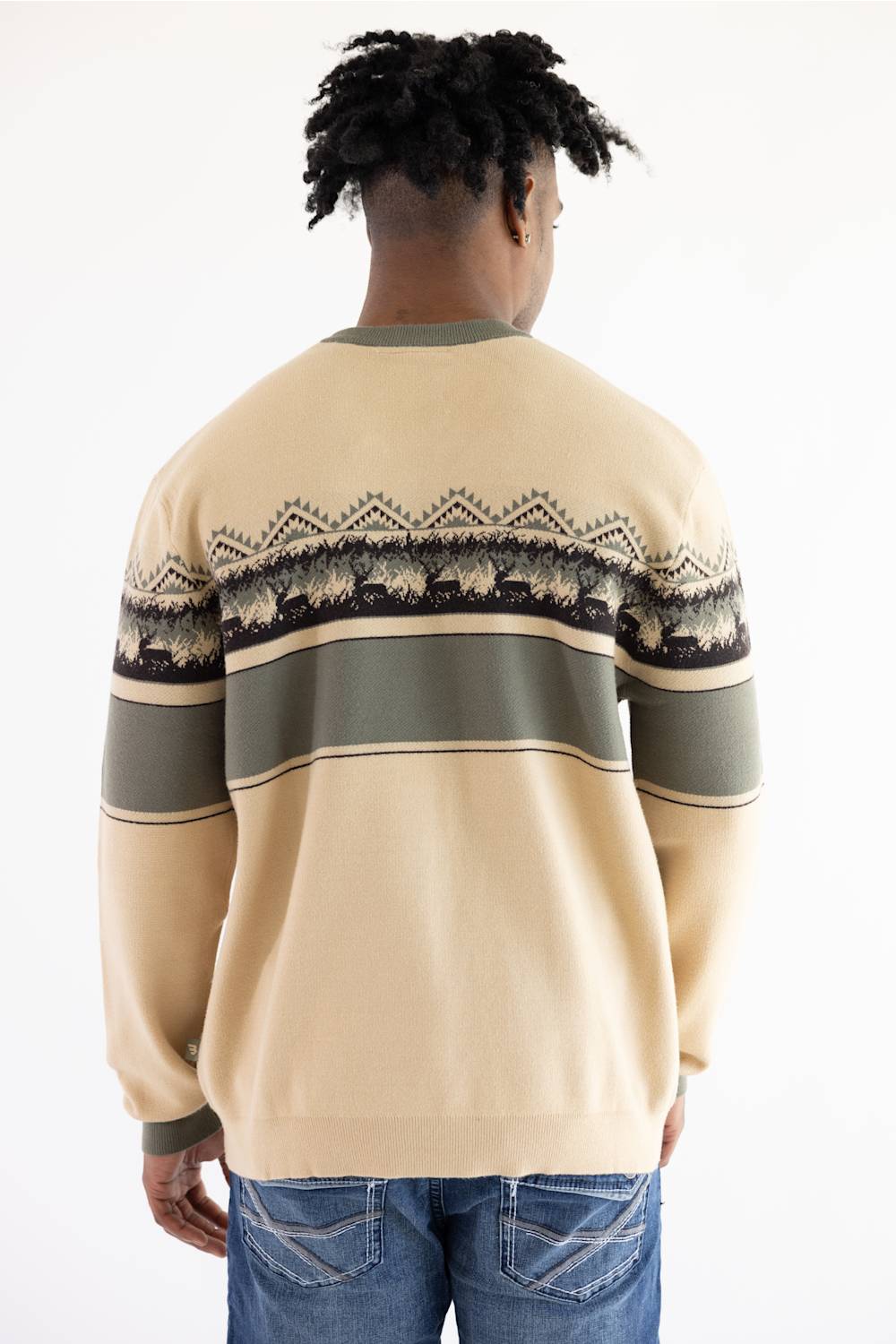 A man viewed from behind wearing a beige crewneck sweater with horizontal stripes and a geometric pattern across the shoulders and upper back, paired with blue jeans against a plain white background.