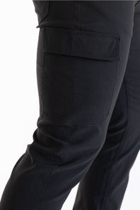 Close-up of a person's leg wearing black cargo pants, showing a side pocket detail against a plain white background.