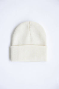 A cream-colored ribbed knit beanie hat with a folded cuff, shown flat against a plain white background.