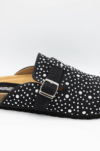 A close-up of a black clog-style mule shoe embellished with silver rhinestones and featuring a wide strap with a silver buckle, shown on a light gray background.