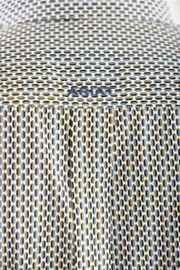 Close-up of a textured metallic mesh surface with a small embossed brand mark reading 'ARIAT'.