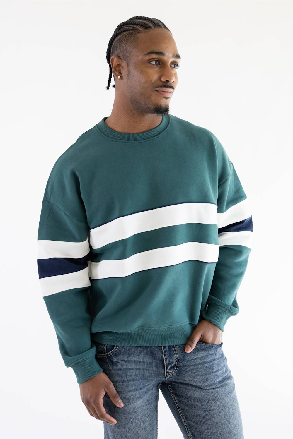 A man viewed from behind wearing a teal colorblock hoodie with white and navy sleeve stripes, paired with light-wash blue jeans, against a plain white background.