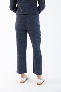 A person shown from the back wearing a matching navy corduroy hoodie and lounge pants, paired with white sneakers, against a plain white studio background.