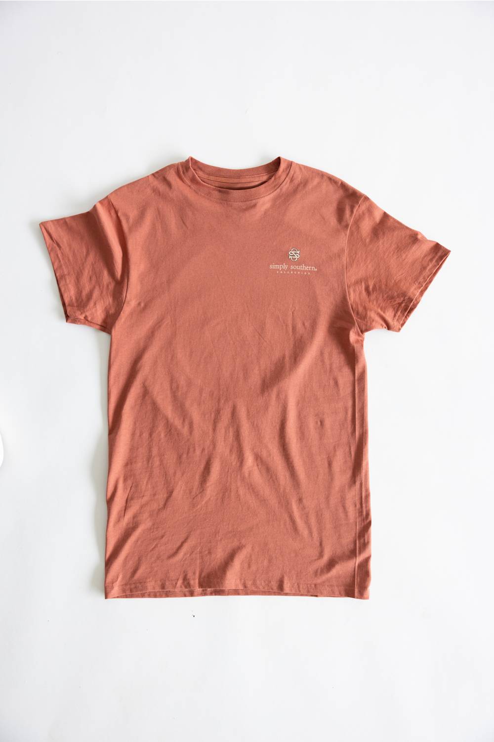 A terracotta-colored short-sleeve crewneck t-shirt with a small white embroidered logo on the left chest, laid flat against a white background.