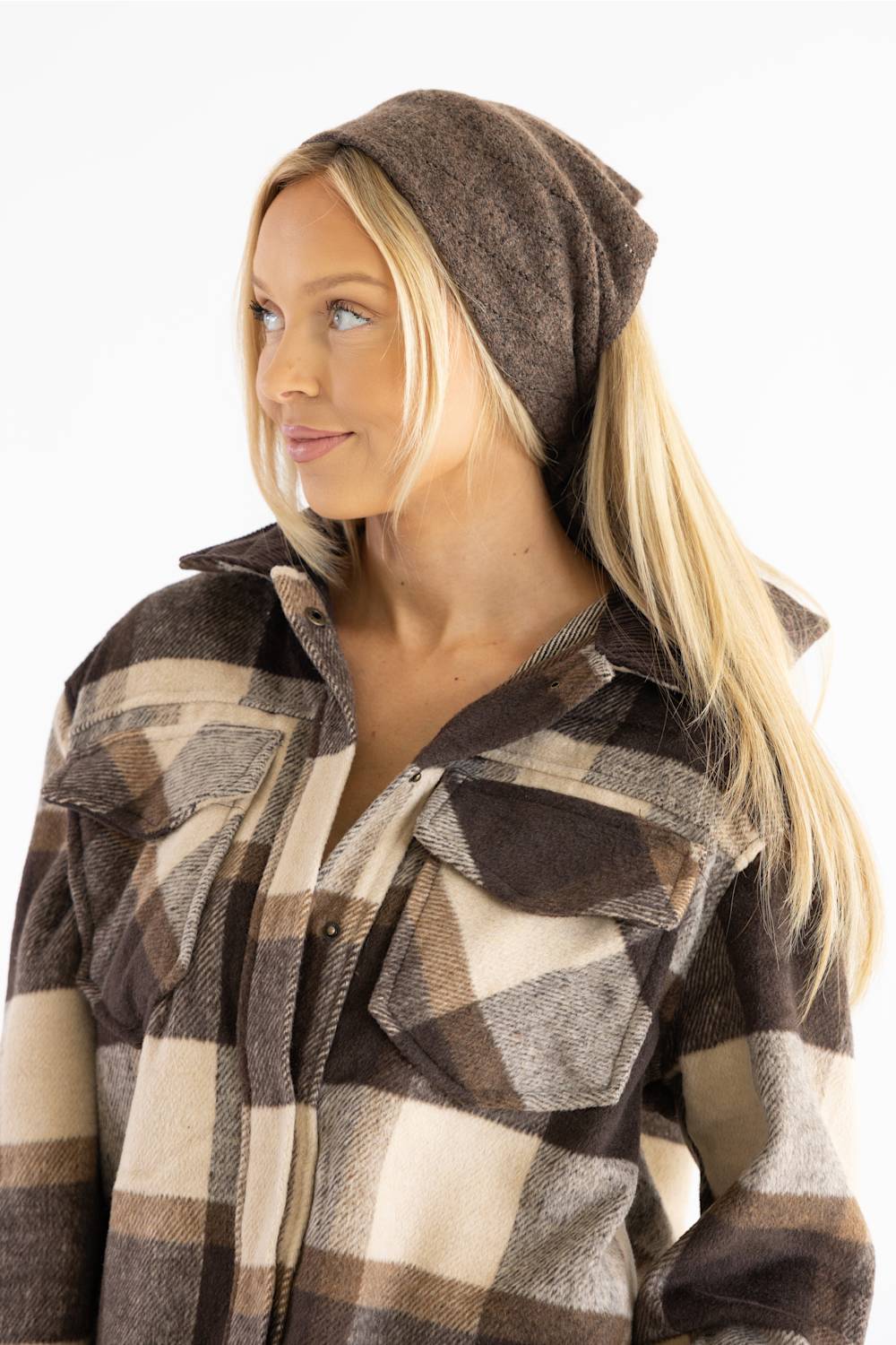 A woman wearing a brown and beige plaid button-up shirt jacket with a matching brown knit beanie, shown against a plain white background.