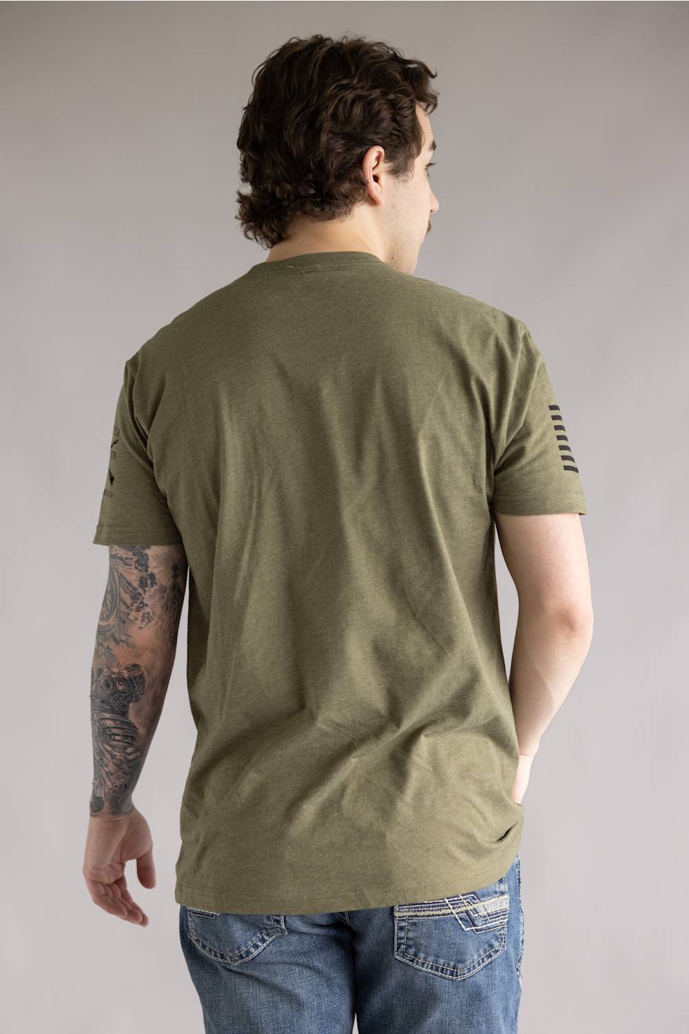 Grunt Style 1776 HR Nightmare T-Shirt for Men in Green; Person wearing an olive green t-shirt with a small flag patch on the sleeve against a plain background