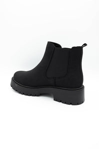 A single black Chelsea-style ankle boot with a chunky lug sole, shown from a side-rear angle on a plain white background.