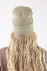 Carhartt Faded Fatigue Olive beanie with red heart patch worn by a smiling woman.