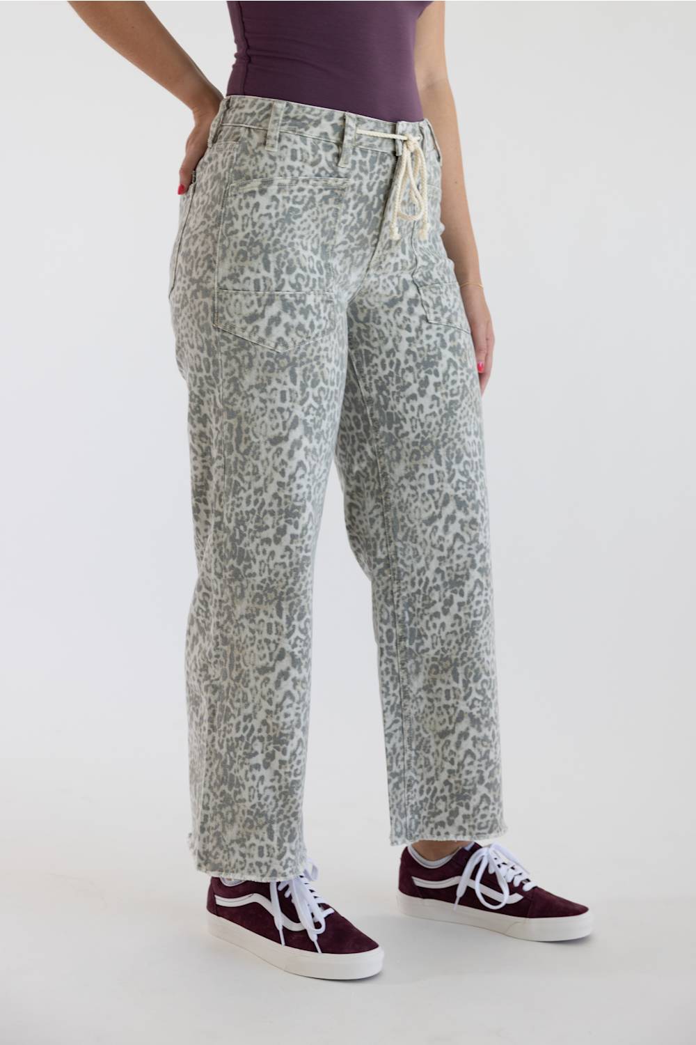 Side angle of high-waisted wide-leg cropped jeans in light grey leopard print, styled with maroon sneakers.