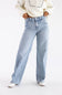 A person wearing light-wash wide-leg blue jeans, a cream knit sweater, and white pointed shoes, standing against a plain white studio background.