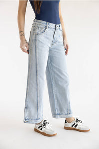 Three-quarter view of Aaron & Amber High Rise Sideseam Detail Wide Leg Jeans in Light Denim, styled with retro low-top sneakers against a plain white background.