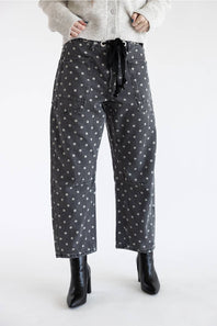 Front view of Aaron & Amber Drawstring Polka Dot Barrel Jeans in black showing full-length barrel silhouette, drawstring tie, and black heeled boots.