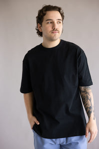 Industrie Del Sur T-Shirt for Men in Black; Man wearing a black t-shirt and blue pants against a plain background