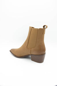 A tan suede ankle boot with a low stacked block heel and a pull tab at the back, shown from a side-rear angle on a white background.