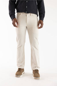 A person wearing light beige straight-leg dress pants, a dark navy long-sleeve button-up shirt, and brown suede shoes, shown from the waist down against a plain white studio background.