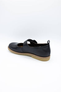 A single black leather Mary Jane shoe with a strap closure and a tan sole, shown from a side-rear angle on a white background.