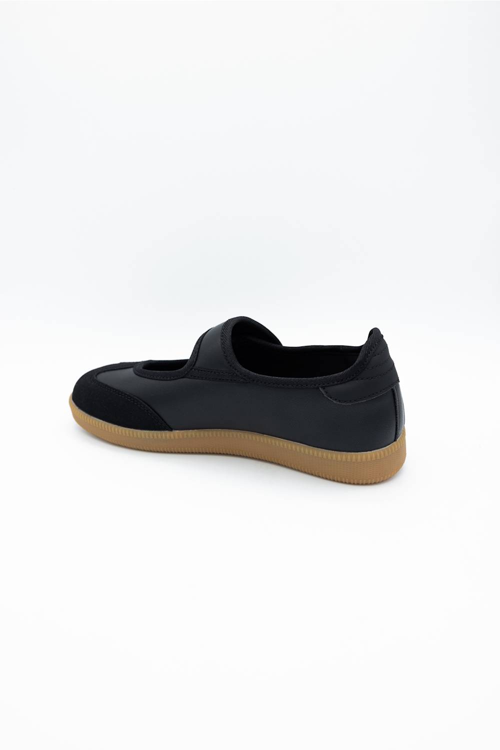 A black slip-on shoe with a tan gum sole, shown from a side profile view against a plain white background.