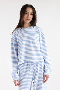 A woman modeling a light blue and white striped long-sleeve top and matching striped pants against a plain white studio background.