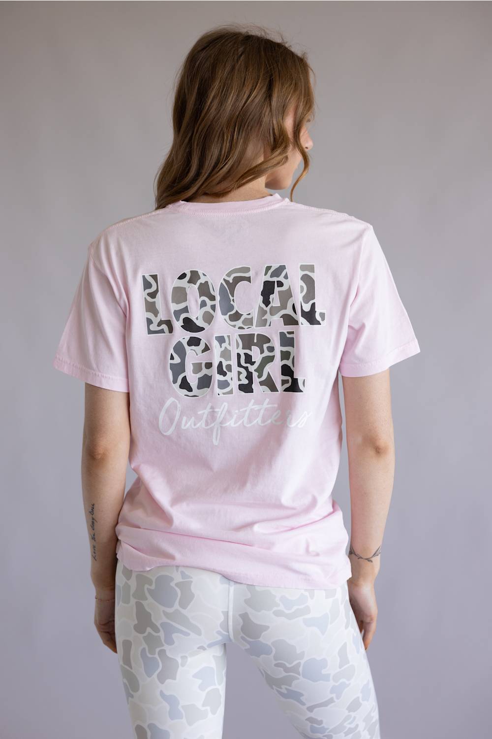 Local Girl Absolute Localflage T-Shirt for Women in Blossom; Person wearing a pink t-shirt with camo print text on the back against a plain background