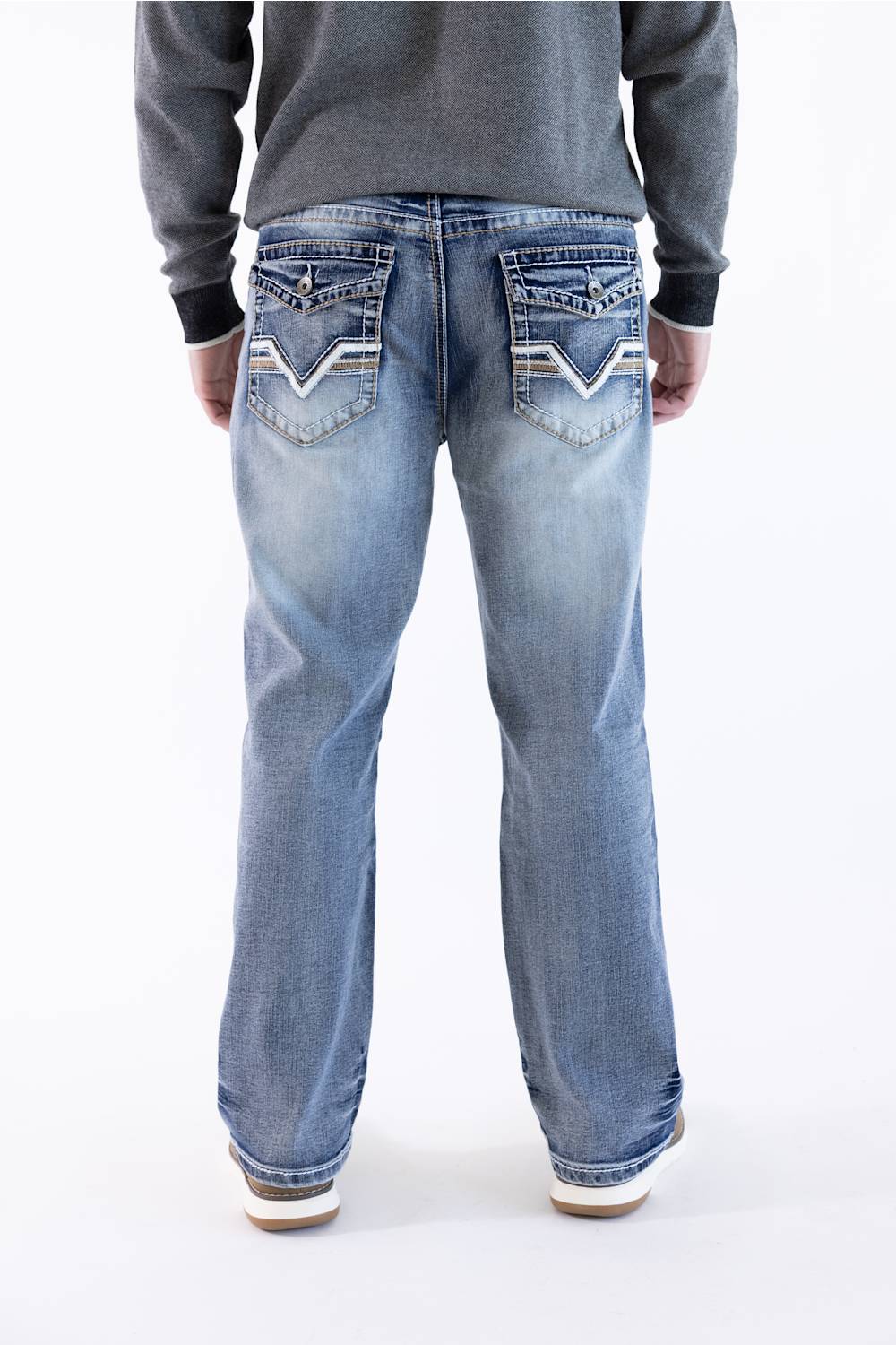 Rear view of a male model wearing True Luck Mac Loose Straight medium-wash jeans featuring embroidered flap back pockets and whiskering, paired with a grey long-sleeve sweater against a plain white background.