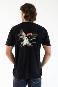 A man viewed from behind wearing a black t-shirt with a large graphic on the back featuring a mallard duck and the text 'LOCAL BOY OUTFITTERS EST. 2013'.