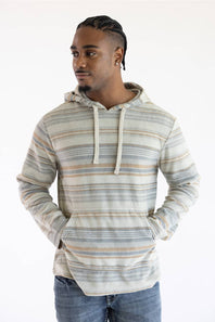 A man wearing a long-sleeve striped hoodie with a textured knit pattern in beige, gray, and white, paired with blue jeans, against a plain white background.