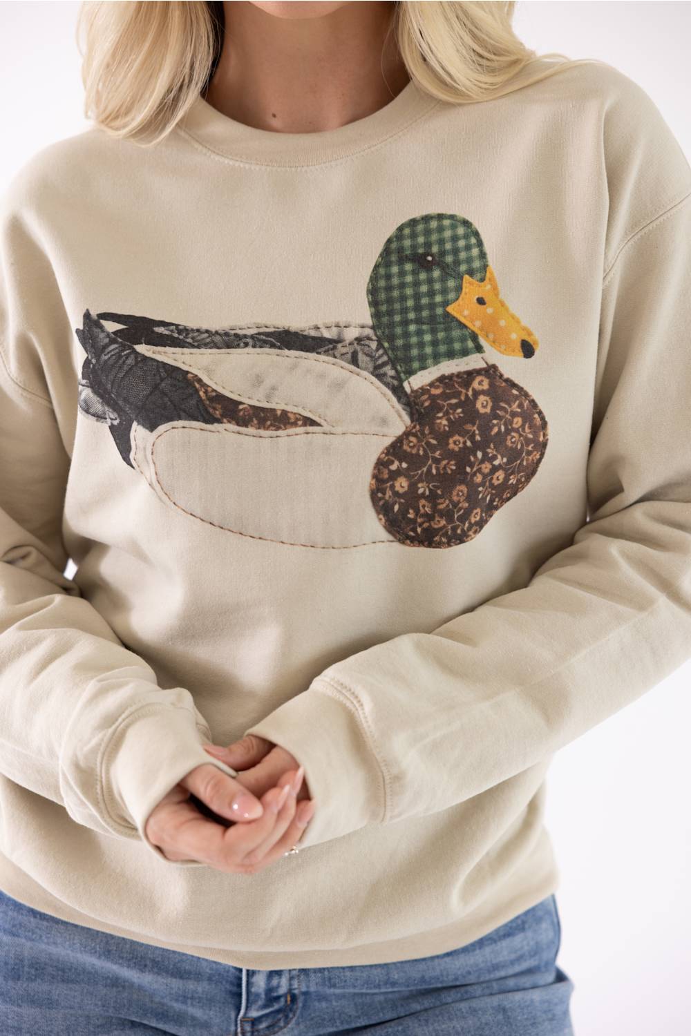 Close-up product shot of the Mallard Duck Sweatshirt for Women in Cream, highlighting the detailed patch-stitch mallard duck graphic with plaid and floral patterned fabric details.