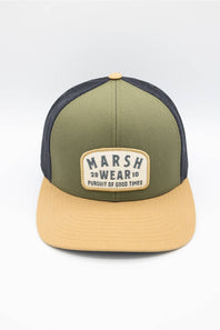 A two-tone trucker cap with an olive green front panel and brim, dark navy mesh back panels, and a tan snapback closure. The front features a cream-colored patch with the text 'MARSH WEAR 2010'.