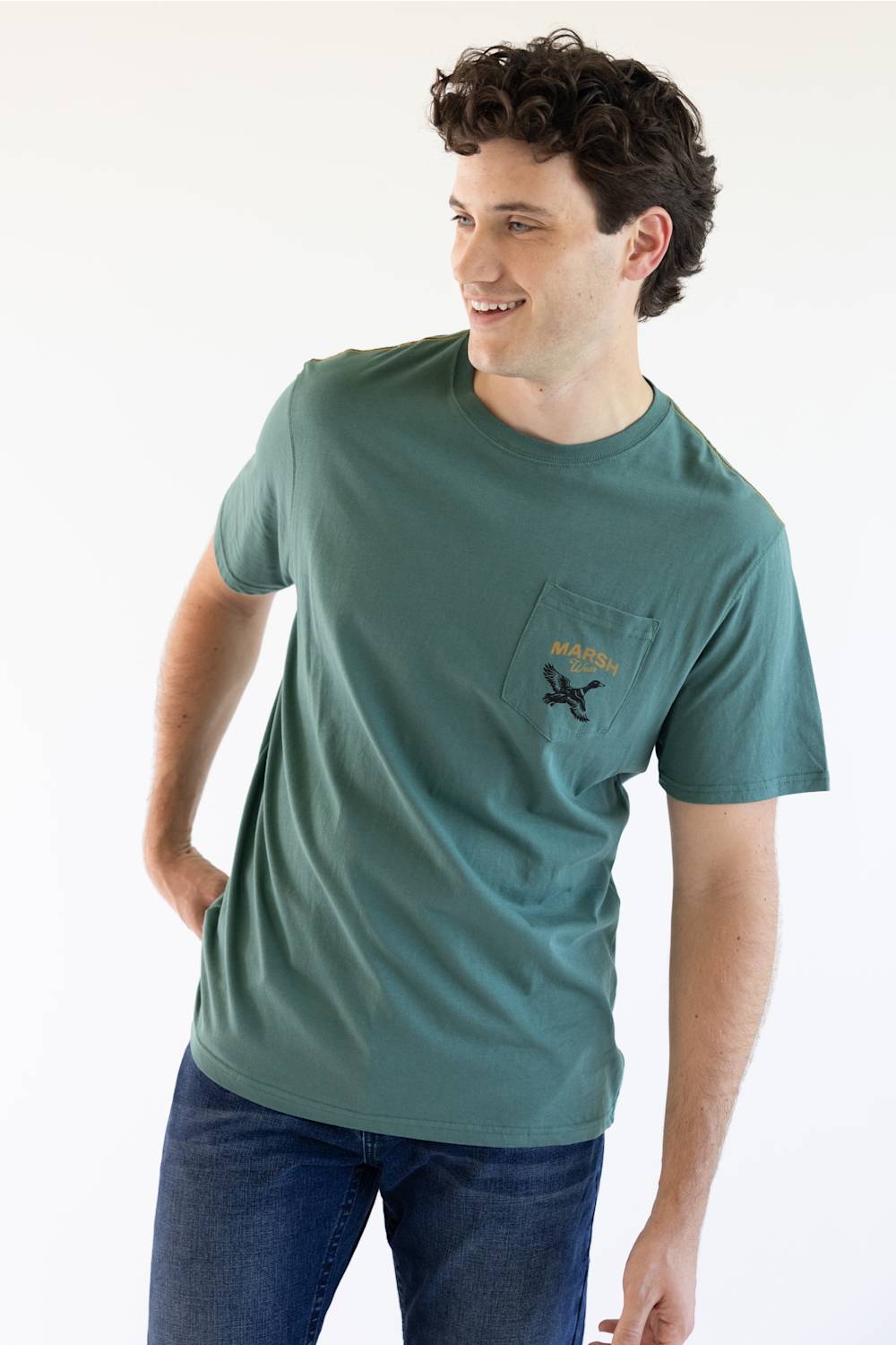 A man viewed from behind wearing a teal green t-shirt with a large black graphic on the back reading 'MARSH Wear' and 'EST. 2010 USA', featuring a flying duck and a circular gold emblem.