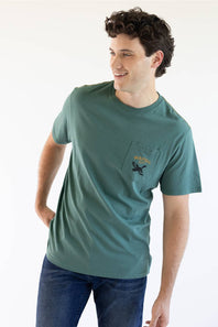 A man viewed from behind wearing a teal green t-shirt with a large black graphic on the back reading 'MARSH Wear' and 'EST. 2010 USA', featuring a flying duck and a circular gold emblem.