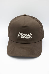 A man wearing a brown trucker hat with 'Marsh Wear' embroidered in white on the front, paired with a brown hoodie, against a plain white background.
