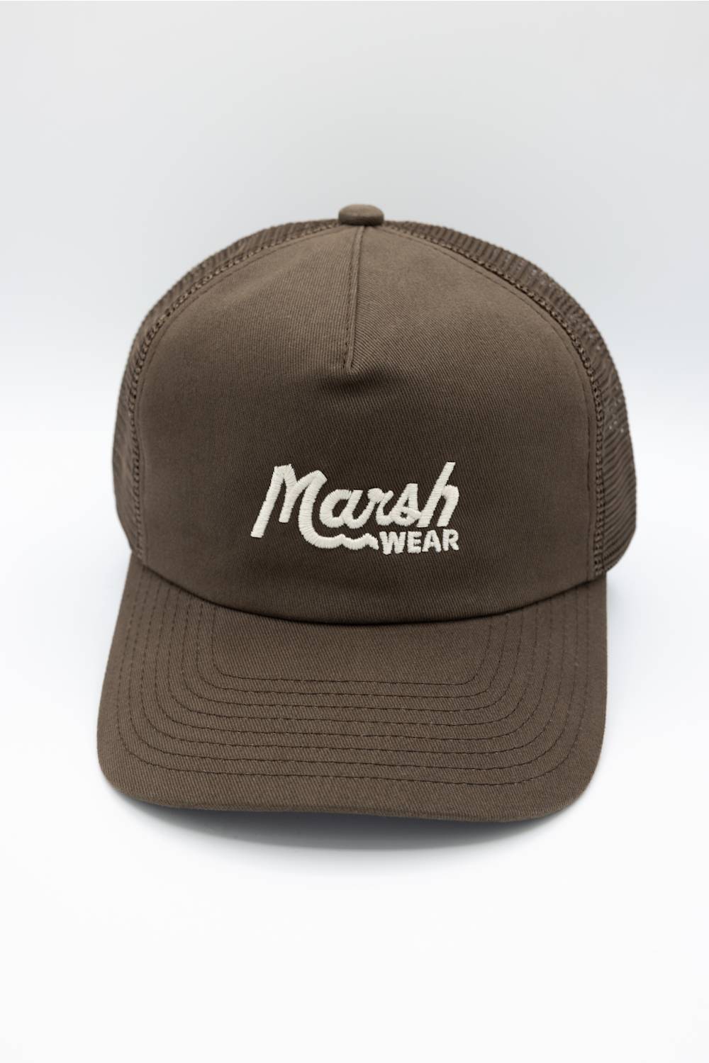 A man wearing a brown trucker hat with 'Marsh Wear' embroidered in white on the front, paired with a brown hoodie, against a plain white background.