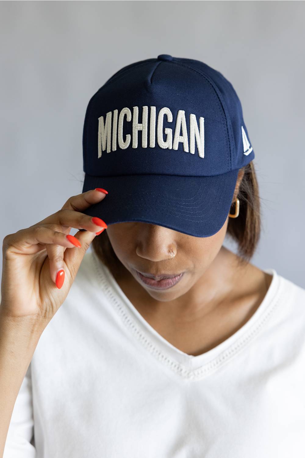 Michigan 3D Stitch Dad Hat in Navy; Person wearing a navy blue cap with 'MICHIGAN' text on a plain background