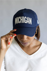 Michigan 3D Stitch Dad Hat in Navy; Person wearing a navy blue cap with 'MICHIGAN' text on a plain background