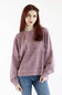 A woman with red hair wearing a faded dusty rose/mauve crewneck sweatshirt and blue jeans, standing against a plain white studio background.