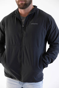man standing in front of a white background  in a patagonia jacket 