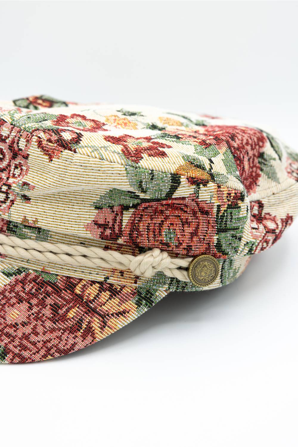 up-close of floral newsboy hat, with rope and button detail