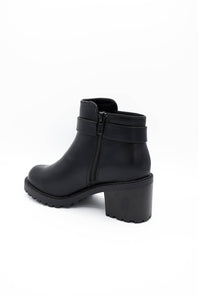 A black leather ankle boot with a chunky block heel, side zipper, and a decorative strap detail around the ankle, shown from a side profile on a white background.