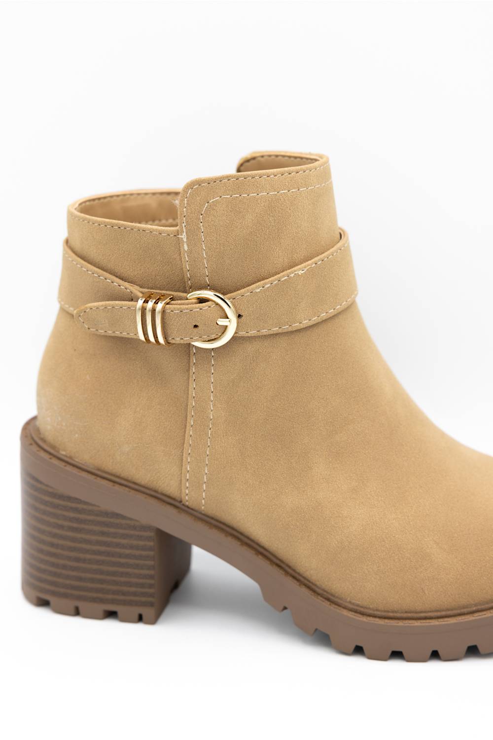 A tan suede ankle boot with a brown block heel, a matching brown lug sole, and a decorative strap with a gold buckle around the ankle.