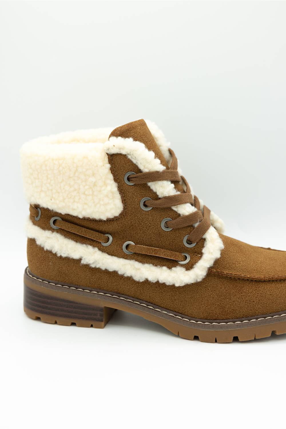 A brown suede lace-up ankle boot with a thick cream-colored shearling lining and a brown lug sole, shown from a side profile on a light gray background.