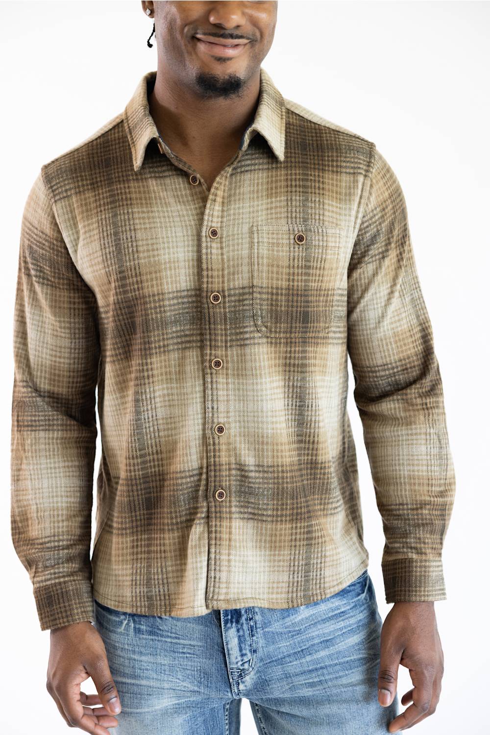 A man wearing a brown and beige plaid long-sleeve button-down shirt with blue jeans, shown from the waist up against a plain white background.