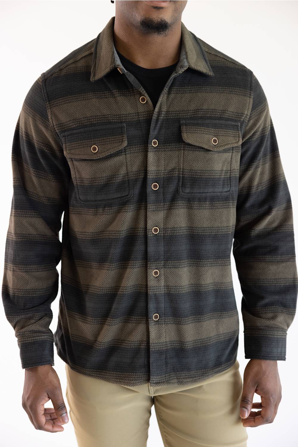 A man wearing a long-sleeve button-up flannel shirt with horizontal brown and black stripes, paired with khaki pants, against a plain white background.