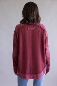 Woman wearing a maroon sweatshirt with a plain background