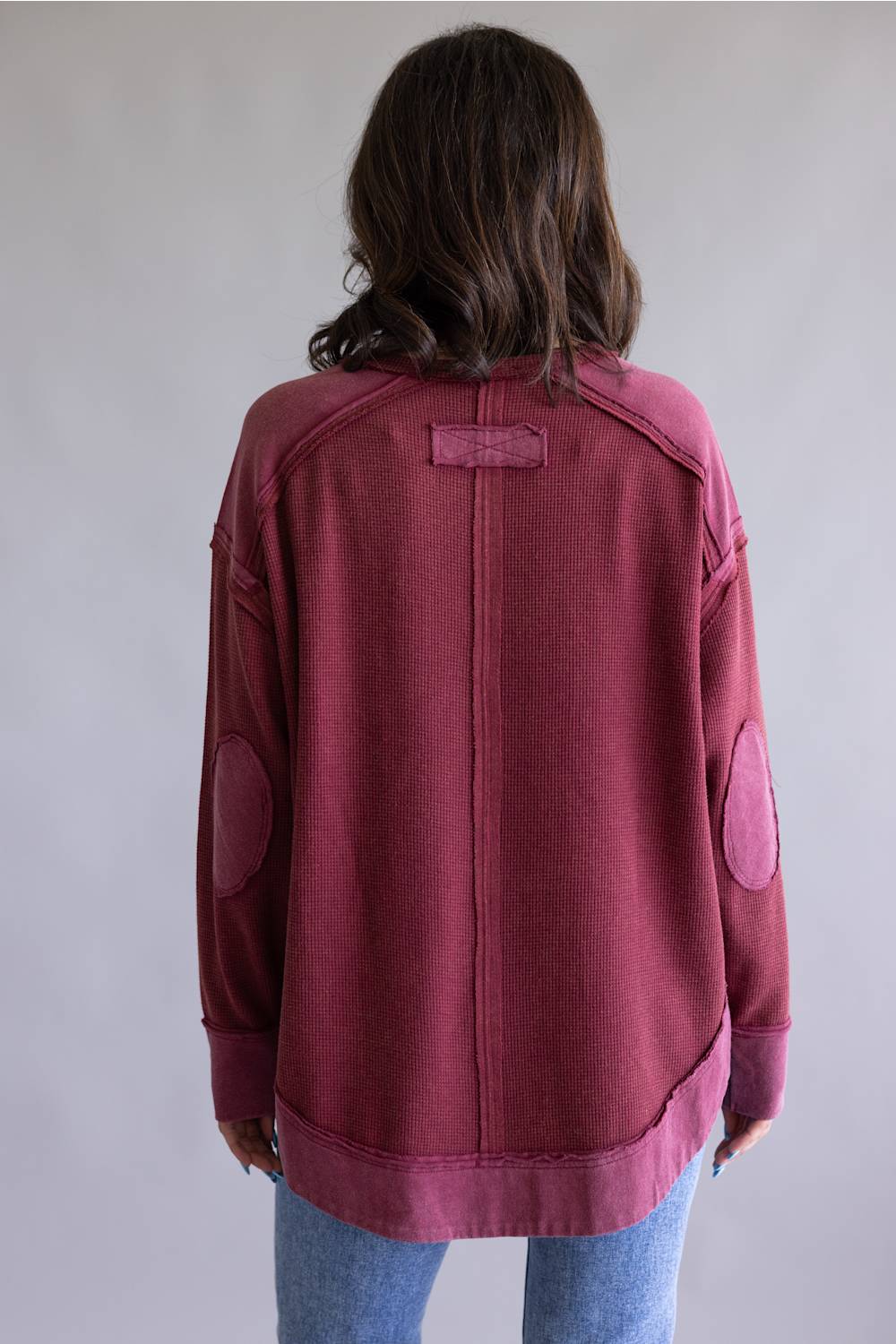 Woman wearing a maroon sweatshirt with a plain background